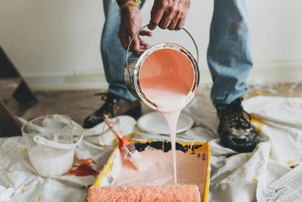 A man pouring paint into a paint tray