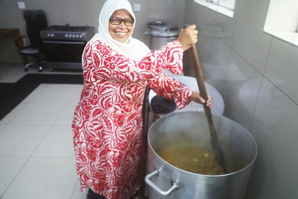 A woman prepares food in a very large cooking pot
